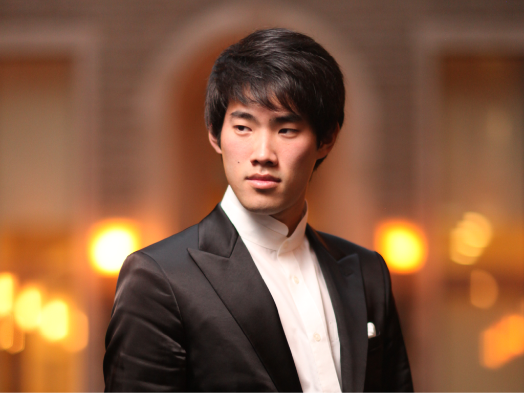 Bruce Xiaoyu Liu, pianist standing wearing a black suit