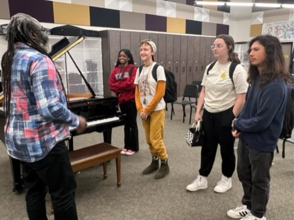A group of people standing around a piano.
