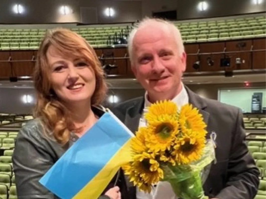 A man and woman holding flowers in front of an audience.