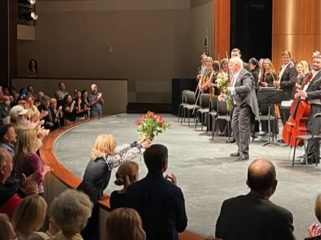 A man and woman are holding roses in front of an audience.